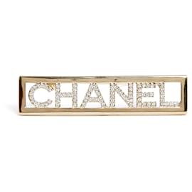 Spilla Chanel in metallo dorato con strass bianchi