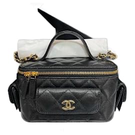 Chanel Pequeño estuche de tocador con asa superior y cadena en negro. Este elegante estuche está hecho de lujosa piel de cordero en negro. La bolsa cuenta con una correa de hombro de cadena dorada entrelazada en cuero y herrajes dorados. El bolso presenta un cierre de cremallera envolvente de 3/4 que se abre a un interior de cuero negro con ranuras para tarjetas, un soporte para cosméticos y un espejo. Longitud de la base: 6.25 in  Altura: 3.75 in  Ancho: 3.00 in  Caída: 1.75 in  Caída: 22.50 in