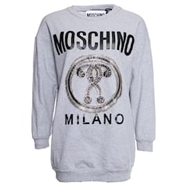 Suéter gris de Moschino con alfileres de seguridad.