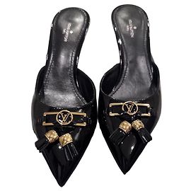 Mules Insider Louis Vuitton en cuero negro brillante con borlas y logo LV