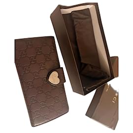 Cartera Gucci de cuero marrón con monograma y cierre de corazón