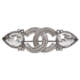 Spilla Chanel logo CC in metallo tono argento e cristalli