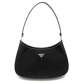 Inspirada en el sofisticado archivo de Prada, una silueta curva moderna armoniza con el icónico ornamento del logotipo triangular de metal para crear un ambiente minimalista pero clásico. Fabricado en cuero cepillado con un