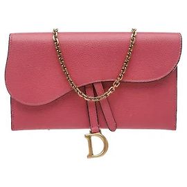 Una modella che mostra il distintivo design del lembo asimmetrico tridimensionale di Dior e l'ornamento in metallo firma. Il materiale in pelle opaca e liscia emana un'aura lussuosa, con slot per carte e una cerniera