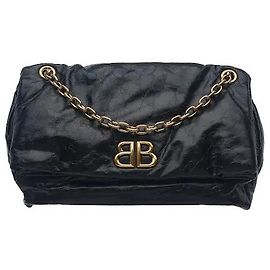 Balenciaga Un modello che armonizza materiale in pelle morbida, lussuosa e flessibile con un classico cinturino a catena in metallo e un ornamento logo in metallo sottilmente brillante. La struttura con chiusura a patta che offre un generoso spazio di archiviazione è