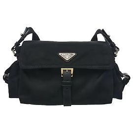 Prada Um produto que adiciona uma silhueta suave e uma configuração multi-bolsos prática ao material Re-Nylon leve e durável. O logótipo triangular em metal esmaltado e os pormenores em pele na aba frontal adicionam