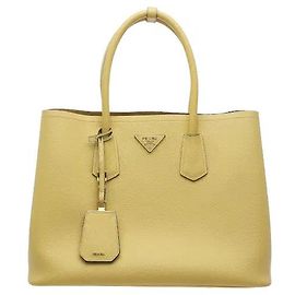 Un produit harmonisant le cuir Saffiano, distingué par sa texture croisée, avec une silhouette structurée. Le logo en lettres métalliques à l'avant et les doubles poignées épurées ajoutent la touche distinctive de Prada.