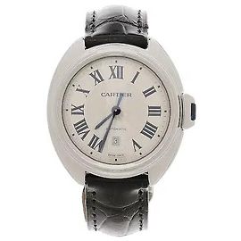 Cartier Ein Produkt, das sich durch ein Gehäuse mit anmutigen Kurven und ein markantes Kronendesign mit einem Schlüsselmotiv auszeichnet. Römische Ziffern und blaue Zeiger sind harmonisch auf einem silbernen Zifferblatt angeordnet, um