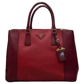 mala Prada Galleria couro Saffiano vermelho, mala Prada em couro Saffiano bicolor vermelho e bordô, com fecho de correr, forro interior em cetim, um bolso interior com fecho e um bolso aplicado. A mala é adornada com o logótipo triangular da Prada em metal dourado.
