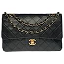 The coveted Chanel Timeless Medium bag 25 cm with lined flap in black leather, garniture en métal doré