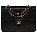 The coveted Chanel Timeless/Classic medium bag 25 cm with lined flap in black leather, garniture en métal doré