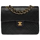The coveted Chanel Timeless/Classic medium bag 25 cm with lined flap in black quilted leather, garniture en métal doré