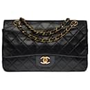 The coveted Chanel Timeless Medium bag 25 cm with lined flap in black leather, garniture en métal doré