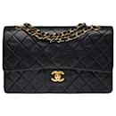 The coveted Chanel Timeless Medium bag 25 cm with lined flap in black quilted leather, garniture en métal doré