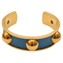 Pulsera rígida abierta de cuero azul grabado vintage de Hermès en metal chapado en oro.