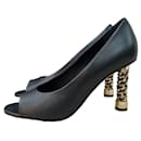Sapatos de salto alto Chanel de couro preto com bico aberto.