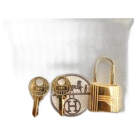 Hermès-Hermès gold-plated steel padlock with two keys, brand new under film with its dustbag for Kelly or Birkin.-Gold hardware