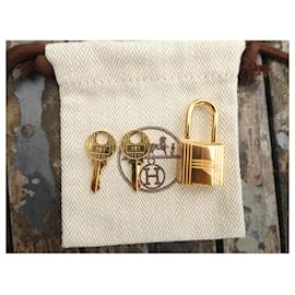 Hermès-Hermès gold-plated steel padlock with two keys, brand new under film with its dustbag for Kelly or Birkin.-Gold hardware